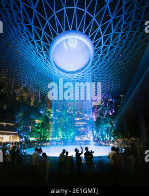 Der Jewel Changi Airport in Singapur bei Nacht. Ein Mischnutzungskomplex mit einem Regenwirbel, dem größten Indoor-Wasserfall der Welt. Stockfoto