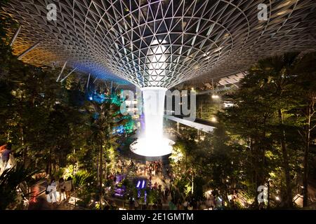 Der Jewel Changi Airport in Singapur bei Nacht. Ein Mischnutzungskomplex mit einem Regenwirbel, dem größten Indoor-Wasserfall der Welt. Stockfoto