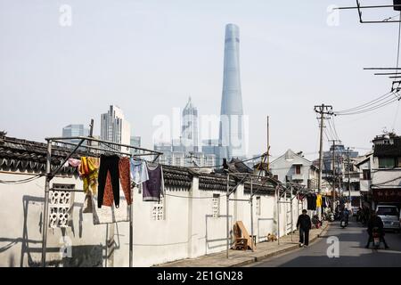 Alt trifft neu, eine Shanghai-Hinterstraße mit dem Shanghai Tower im Hintergrund. Stockfoto