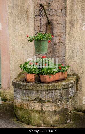 Steinerne Blumenkästen auf einem alten Brunnen in einem kleinen Dorf in Burgund, Frankreich Stockfoto