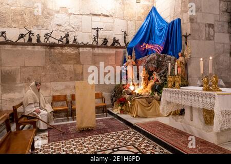 Ein Christ, der als Jesus Christus gekleidet ist, sitzt vor einer Weihnachtsvorlesung in der römisch-katholischen Kapelle des Allerheiligsten Sakraments in der Grabeskirche in Jerusalem, Israel Stockfoto