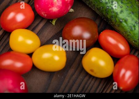 Grüne Gurken, reife Radieschen und bunte Tomaten verstreut auf dem Tisch. Nahaufnahme, selektiver Fokus Stockfoto