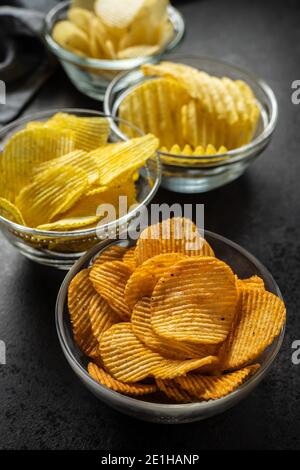 Knusprige Kartoffelchips mit verschiedenen Geschmacksrichtungen in Schüssel. Stockfoto