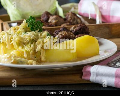 Kohl in Bechamelsauce serviert mit Kartoffeln und Fleischbällchen Stockfoto