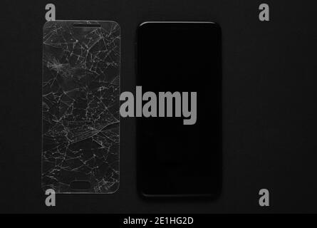 Smartphone mit gebrochenem Schutzglas auf schwarzem Hintergrund Stockfoto