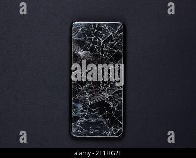 Smartphone mit gebrochenem Schutzglas auf schwarzem Hintergrund Stockfoto