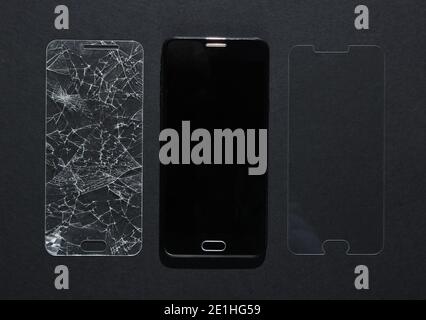 Smartphone mit gebrochenem und neuem Schutzglas auf schwarzem Hintergrund. Draufsicht Stockfoto