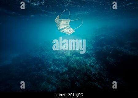 Chirurgische Maske schwimmend im Meer. Konzept der Verschmutzung und nicht biologisch abbaubare Abfälle. Stockfoto