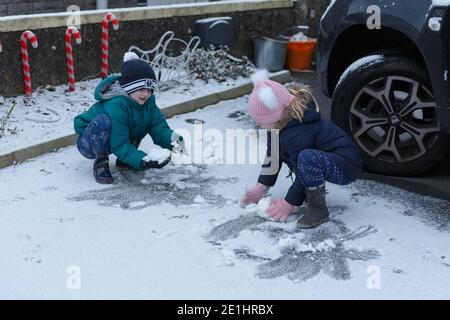 Cork, Irland. Januar 2021. Snow Falls auf Cork City. Charlie und Abbie McCleverty (Ballyvolane) spielen im Schnee. Die Einwohner von Cork sind heute Morgen nach einem kurzen Schneeschauer in der Stadt und den Vororten aufgewacht, die von einer Schneedecke bedeckt waren. Viele haben sich in Mäntel und Hüte eingewickelt und gingen hinaus, um die frische Luft zu genießen und die schönen Szenen zu sehen. Kredit: Damian Coleman/Alamy Live Nachrichten Stockfoto