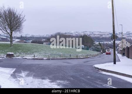 Cork, Irland. Januar 2021. Snow Falls auf Cork City. Der Bus 207 fährt die Ballincollie Road hinunter, gefolgt von einem Fußgänger, der den Wegen trotzt. Die Einwohner von Cork sind heute Morgen nach einem kurzen Schneeschauer in der Stadt und den Vororten aufgewacht, die von einer Schneedecke bedeckt waren. Viele haben sich in Mäntel und Hüte eingewickelt und gingen hinaus, um die frische Luft zu genießen und die schönen Szenen zu sehen. Kredit: Damian Coleman/Alamy Live Nachrichten Stockfoto