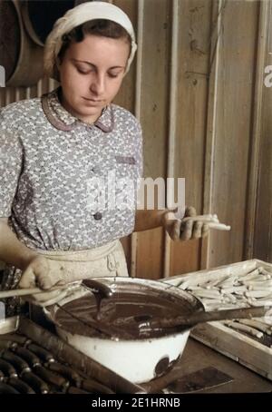 Deutschland - Deutschland Ca. 1951, Sachsen-Anhalt, Zuckerwarenfabrik in Zeitz, Arbeiterin bei der Herstellung von Schokoladenüberzug. Arbeitnehmer die Verarbeitung einer schokoladenglasur zu einem Zucker erzeugenden Unternehmen in Zeitz, Deutschland Ca. 1951. Stockfoto