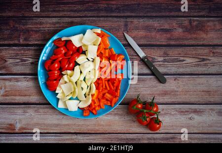 Frisch geschnittenes Gemüse (Tomaten, Fenchel und Paprika) mit Küchenmesser auf einem rustikalen Holztisch. Vorbereitung für gesundes Kochen zu Hause. Stockfoto