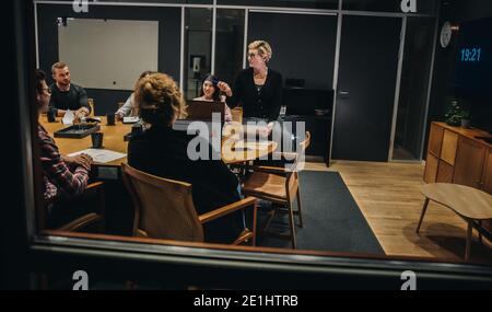 Geschäftsleute im Besprechungsraum diskutieren das Projekt. Frau leitet Geschäftstreffen und diskutiert den Plan. Stockfoto