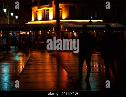 Romantisches Nachtleben Paris im Herbst. Verschwommene Nachtansicht des Pariser Platzes nach Regen. Bunte Lichter spiegeln sich auf nassem Bürgersteig. Silhouette des Gehens Stockfoto