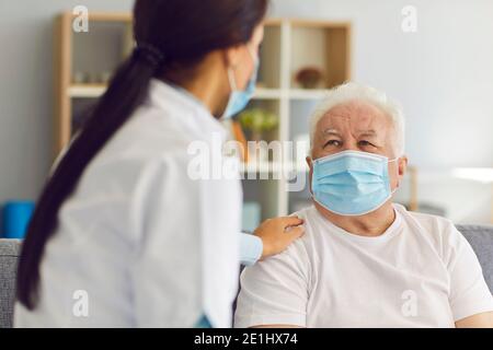 Ältere ältere Mann Patient in medizinische Maske bekommen Unterstützung Ärztin Stockfoto