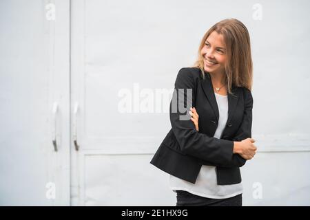 Außenportrait der glücklichen modernen Geschäftsfrau. Blonde Geschäftsfrau steht draußen und lächelt. Stockfoto