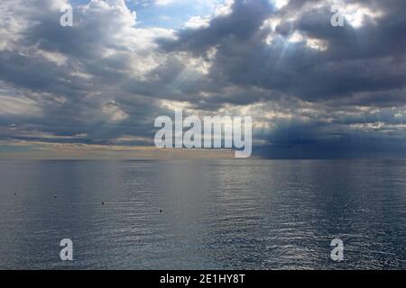 Sonnenstrahlen, die durch die Sturmwolken über das Meer ziehen Stockfoto