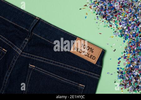 Recycelte blaue Jeans mit einem Kleidungsanhänger. Kreislaufwirtschaftsprinzip, Zero Waste Konzept. Wiederverwendung von Materialien und Reduzierung von Abfall in der Mode. Textil hergestellt Stockfoto