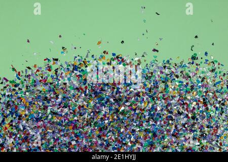 Recycelte Suppenpellets aus Plastik aus dem Meerwasser, flachgelegt auf grünem Hintergrund. Bunte Stücke und Texturen. Umdenken der Umgebung b Stockfoto
