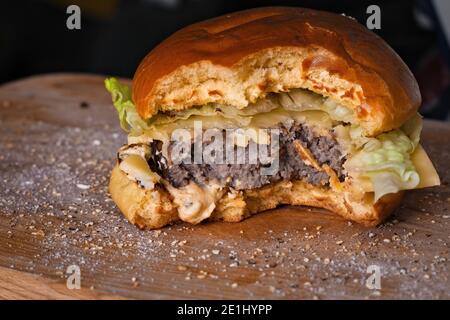 Hausgemachter Gourmet-Cheeseburger mit Happen aus Romaine-Salat, reifem Cheddar-Käse und Hummus Stockfoto