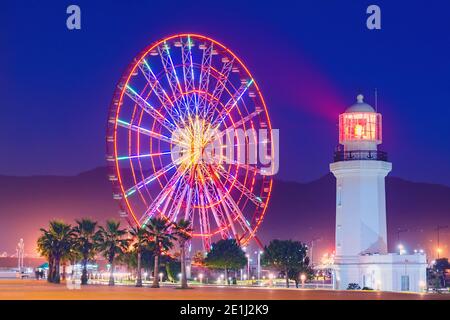 Riesenrad im Vergnügungspark am Abend. Batumi Boulevard. Das Foto wird mit einer langen Belichtung aufgenommen und hat Bewegungsunschärfen. Stockfoto