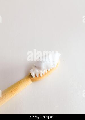 Mikroplastikpartikel in einem Zahnpasta-Abstrich auf einer Zahnbürste aus Holz. Darstellung des Mikroplastik-Problems in Körperpflegeprodukten. Stockfoto