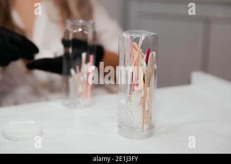 Werkzeuge für dauerhafte Make-up in der Flasche im Fokus und verschwommene Hände der weiblichen Meister in schwarzen Handschuhen auf dem Hintergrund. Sterilität der Tattoo-Instrument Stockfoto