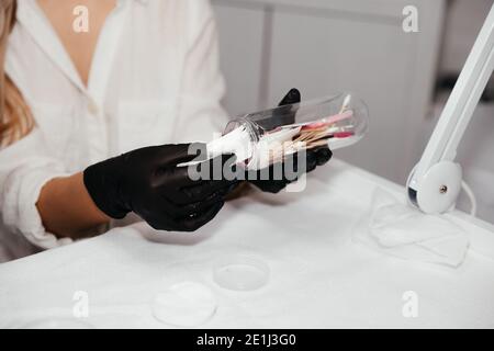 Werkzeuge für dauerhafte Make-up in der Flasche in den Händen der weiblichen Meister in schwarzen Handschuhen, selektiver Fokus. Kosmetikerin Werkzeuge für die Herstellung Augenbrauen Make-up. Stockfoto