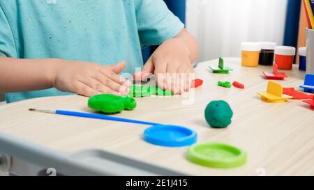 Nahaufnahme von kleinen Jungen bilden und Formen bunte Plastilin oder Ton mit Händen. Spezieller farbenfroher Teig zur Verbesserung der motorischen Fähigkeiten von Kindern. Kind Stockfoto