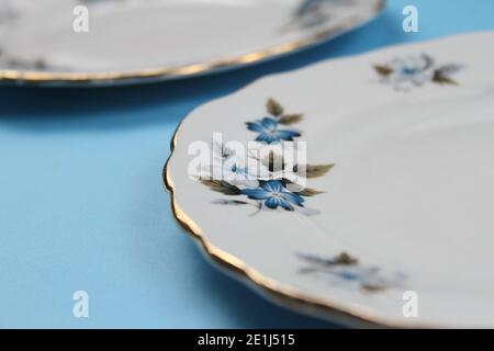 Nahaufnahme eines goldbemalten Tellers mit blauen Blüten Vor einem schlichten Hintergrund Stockfoto