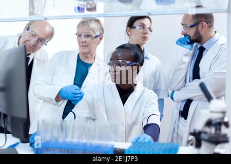 Chemiker Biologen, die medizinische Analyse mit Computer. Afrikanischer Gesundheitsforscher im Labor für Biochemie, der sterile Geräte trägt. Stockfoto