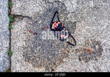 Verlorene oder verlassene, schwarze Gesichtsmaske mit Bild der Hand, die während der Corona-Pandemie Lippenstift auf den Pflaster aufsetzt, Mitte, Berlin Stockfoto