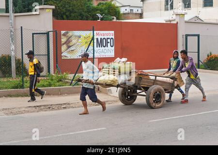 Antananarivo, Madagaskar - 24. April 2019: Unbekannter madagassischer Mann, der auf der Hauptstraße Holzkarren mit Früchten zieht. Es gibt nicht viele Geschäfte in Madagaskar, Stockfoto