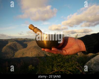 Singende Schüssel in der Hand eines Mannes mit Hintergrund Himmel gehalten Und der Natur Stockfoto