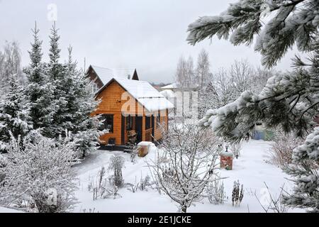 Holzhaus eingerahmt von Bäumen nach Schneefall Stockfoto