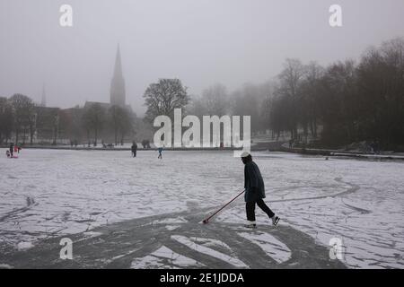 Glasgow, Großbritannien, 7. Januar 2021. Frauen räumt den leichten Schnee von oben auf dem Eis, damit sie Schlittschuh laufen kann, eine Flucht vor dem Lockdown, während einer Reise zum Queen's Park im Süden der Stadt. Foto: Jeremy Sutton-Hibbert/Alamy Live News Stockfoto