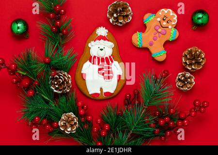 Rote Weihnachten orthodoxe Karte ist mit Lebkuchen in Form eines stilisierten Eisbären geschmückt. Neujahrskarte mit Lebkuchenmann, Tannenbrensch Stockfoto