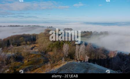 Atemberaubende Winteransicht von Painswick Beacon in den Cotswolds suchen Über das nebelgefüllte Tal zum The Snow Capped Hügel am fernen Horizont Stockfoto