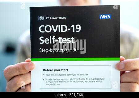 Ein Mann hält Covid-19 Selbsttest Schritt-für-Schritt-Anleitung vor sich. Das Handbuch enthält Anweisungen zur Durchführung des Covid-19-Abstrichtests. Stockfoto