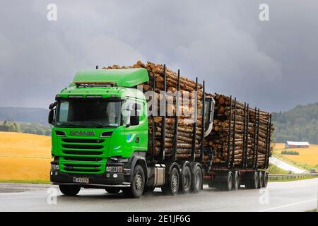 Green Scania R730 LKW zieht Holzanhänger voller Kiefernholz bergauf auf auf der Landstraße an regnerischen Tag. Salo, Finnland. September 2020. Stockfoto