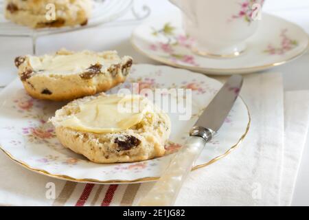 Scones ein klassischer britischer Kuchen gefüllt mit Sultaninen und Rosinen Und wird oft während des Nachmittagstees gebuttert serviert Stockfoto