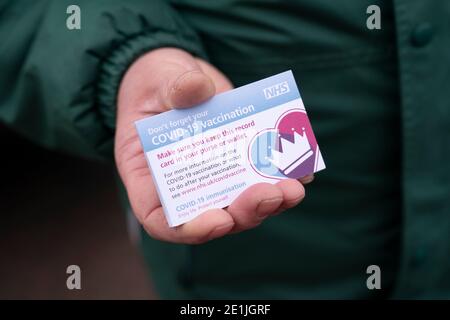 Greater Manchester, Großbritannien. Januar 2021. Ein Mitarbeiter hält am 7. Januar 2021 im Hyde Leisure Center im Großraum Manchester (Großbritannien) Impfkarten, die an die Öffentlichkeit übergeben werden, die ihre zweite Dosis des Pfizer-BioNTech-Impfstoffs COVID-19 erhalten. Der britische Premierminister Boris Johnson sagte den Abgeordneten am Mittwoch, dass die Regierung "jede verfügbare Sekunde" der Sperre nutzen werde, um durch die Einführung von COVID-19-Impfstoffen in den kommenden Wochen einen "unsichtbaren Schutz" um ältere und gefährdete Menschen zu platzieren. Quelle: Jon Super/Xinhua/Alamy Live News Stockfoto