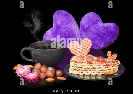 Waffelkuchen mit einem Herz und Trauben dekoriert, und heißen Tee in einer Tasse. Das Konzept des Valentinstag Stockfoto