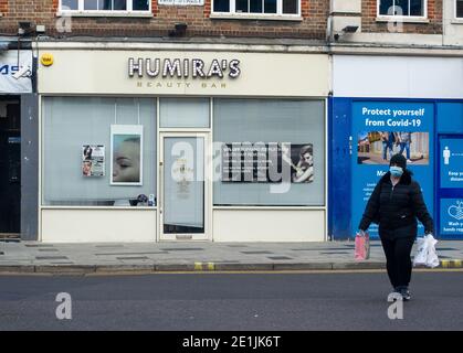 Slough, Berkshire, Großbritannien. Januar 2021. Eine Frau geht an einer geschlossenen Beauty-Bar vorbei. Slough war heute am zweiten Tag der neuen Covid-19 Nationalsperre viel ruhiger als sonst. Die Zahl der positiven Covid-19-Fälle in Slough ist außer Kontrolle geraten. Für die sieben Tage bis zum 2. Januar 2021 waren die Zahlen pro 100,000 für Slough 1064.6 gegenüber 722.2. Die durchschnittliche Zahl in ganz England ist nur 606.9 für den gleichen Zeitraum. Quelle: Maureen McLean/Alamy Live News Stockfoto