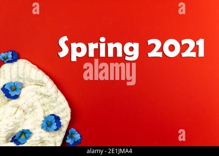 Frühjahr 2021 Hintergrund und Komposition mit Text und Beschriftung, Strickpullover mit dekorativen Blumen auf rot, Konzept, kopieren Raum Foto Stockfoto