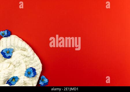 Konzept der Frühling Hintergrund, blaue Blumen und Strickpullover auf rotem Hintergrund, kopieren Raum Banner Foto Stockfoto