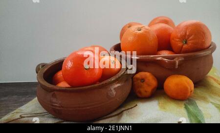 Orangen, Mandarinen Orangen, Mandarinen, alle Zitrusfrüchte in Schale und auf einem ländlichen Küchentisch Stockfoto