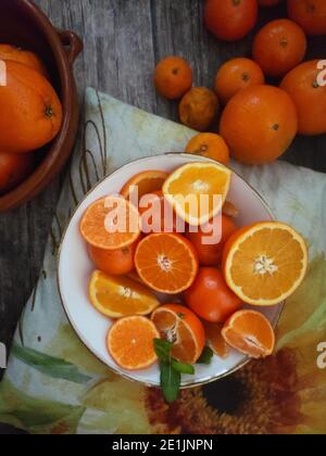 Orangen, Mandarinen Orangen, Mandarinen, alle Zitrusfrüchte in Schale und auf einem ländlichen Küchentisch Stockfoto