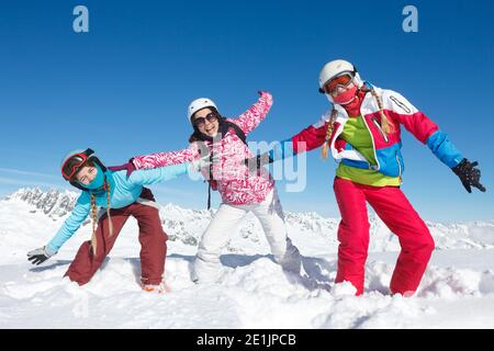 Drei Mädchen im Winterurlaub in den Alpen posieren im Schnee auf den Skipisten. Lustige Aktivität im Schnee Stockfoto