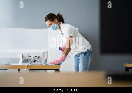 Reinigungsservice Am Schreibtisch. Professionelle Hausmeister In Gesichtsmaske Stockfoto